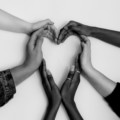 6 hands from different people forming the shape of a heart together
