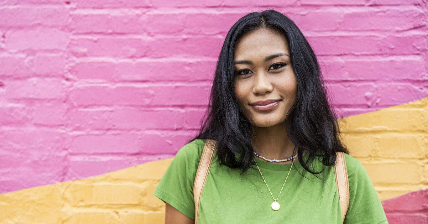 Young generation Z woman standing against brightly colored wall